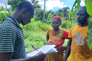 un animateur de wakili rend visite à un couple d'agriculteurs sur leur parcelle
