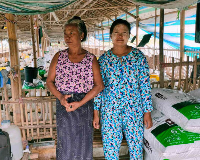 deux commerçantes de Sont Oo Tehtwin posent devant le lieu où elles stockent leurs marchandises