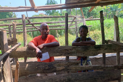 un bénéficiaire d'Elili et sa fille sont devant l'enclos des porcs qu'ils élèvent