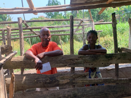 un bénéficiaire d'Elili et sa fille sont devant l'enclos des porcs qu'ils élèvent