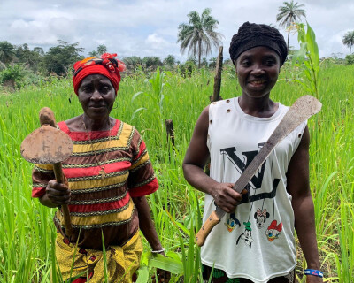 deux agricultrices bénéficiaires d'Elili sont dans un champ et tiennent dans la main leurs outils d
