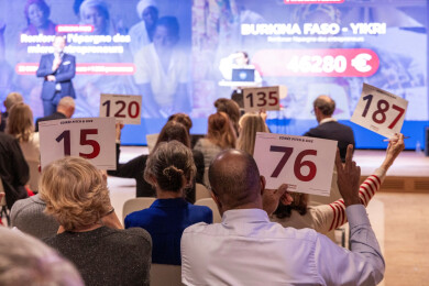 les participants du pitch and give 2025 d'entrepreneurs du monde vus de dos, dont certains lèvent l