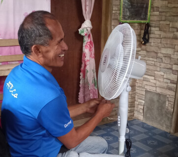 Un technicien d'ATECo aux Philippines installe un ventilateur chez un bénéficiaire.