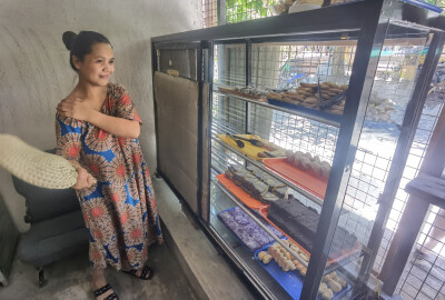 Une pâtissière bénéficiaire d'ATECo aux Philippines pose devant sa vitrine.