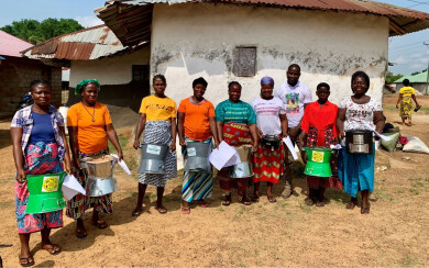 Un groupe de bénéficiaires d'Elili, au Libéria, montrent le réchaud de cuisson qu'elles vont tester