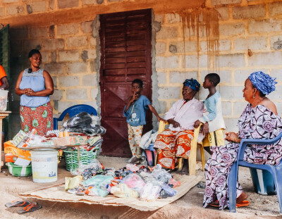 Une bénéficiaire de Wakili en Guinée est devant sa boutique avec des proches