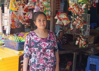 Une bénéficiaire de SOO au Myanmar pose devant son épicerie.