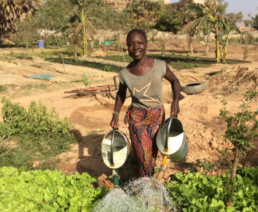 Une femme accompagnée par le projet PDI au Burkina Faso arrose une parcelle de terre