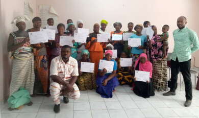 Un groupe femmes tient dans les mains un certificat de formation, aux côtés de deux formateurs, au 