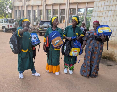 4 femmes burkinabè, dont 3 portant la tenue professionnelle d’Émergence Net, sont devant un bâtimen
