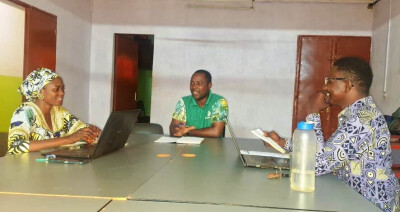 Réunion de travail entre deux hommes et une femme dans un bureau, au Burkina Faso