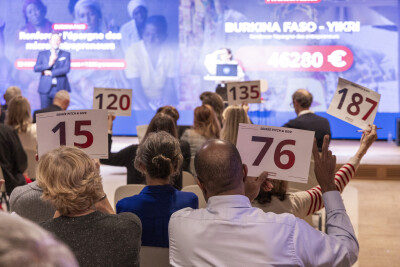 Soirée Pitch&Give 2025 : le public, de dos, lève des pancartes avec un numéro pour soutenir Yikri a