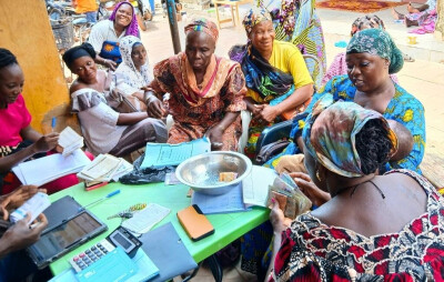 Des femmes accompagnées par Yikri sont assises autour d'une table et déposent leur épargne